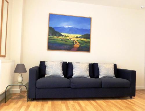 a blue couch in a living room with a painting at Basingstoke Apartments, Alencon Link Executive Serviced Apartments in Basingstoke