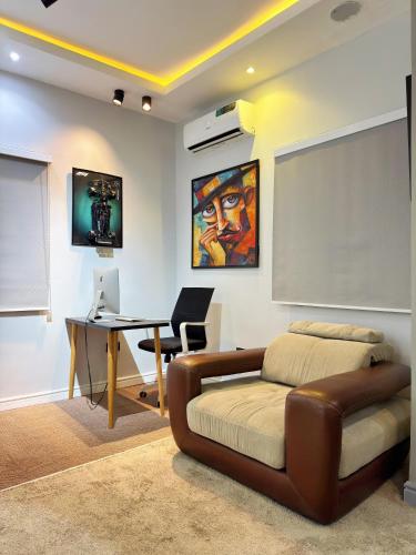 a bedroom with a couch and a desk with a computer at The Nook - Super Luxurious 1 Bedroom in Wuse 2 in Abuja