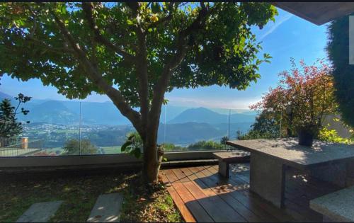 a table and a tree on a balcony with a view at ROMANTIC SUlTE WITH AMAIZING VIEW in Cademario