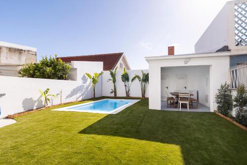 a backyard with a swimming pool and a grass yard at Lazy Point Caparica in Costa da Caparica