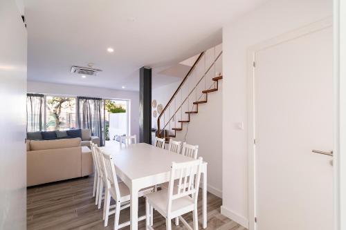 a white dining room with a white table and chairs at Lazy Point Caparica in Costa da Caparica