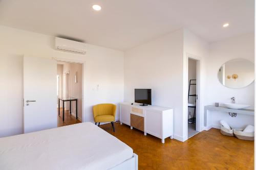 a white bedroom with a bed and a desk and a sink at Lazy Point Caparica in Costa da Caparica