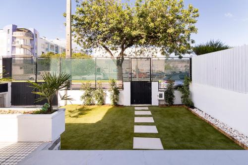 a garden with a white fence and a small yard at Lazy Point Caparica in Costa da Caparica