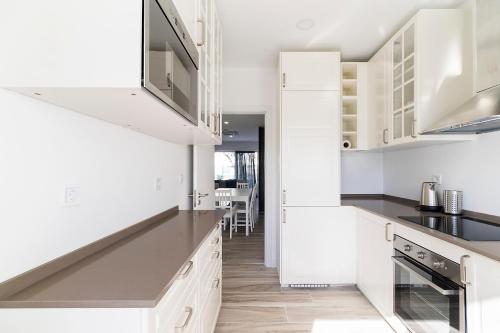 a kitchen with white cabinets and black counter tops at Lazy Point Caparica in Costa da Caparica