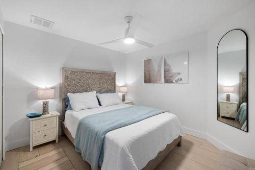 a white bedroom with a bed and a mirror at Heat of Siesta Village Walk to Beach w heated Pool in Siesta Key