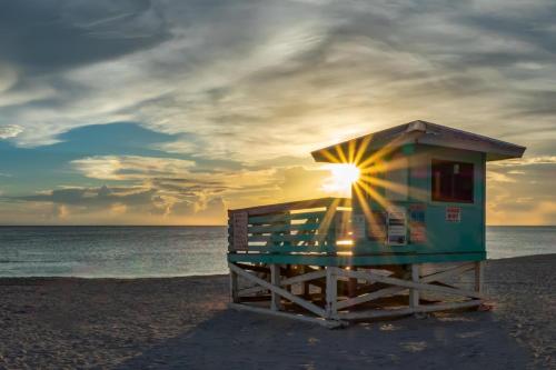 a lifeguard shack on a beach with the sun setting at Heat of Siesta Village Walk to Beach w heated Pool in Siesta Key