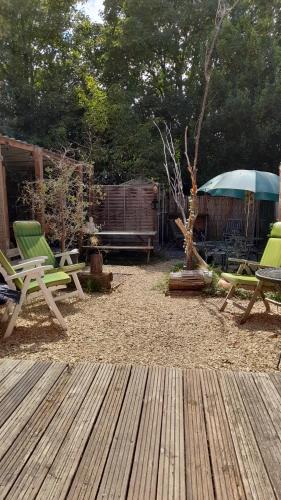 a patio with two green chairs and a wooden deck at Hygge Somerset in Street