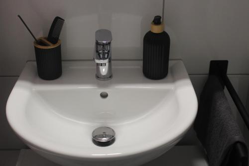 a white sink with two black bottles on top of it at Hilton Apartment Styles in Pforzheim in Pforzheim