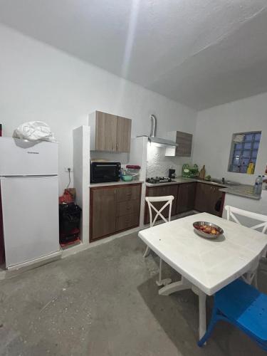 a kitchen with a white table and a white refrigerator at Dar El Amel in Mellita