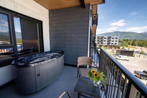 ein Whirlpool auf einem Balkon mit einem Tisch und einer Bank in der Unterkunft Revytalise - Cozy 3 Bedroom Condo in Revelstoke
