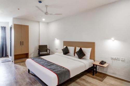 a bedroom with a large white bed and a chair at Super Townhouse RCC Majestic 397 LB Nagar in Hyderabad