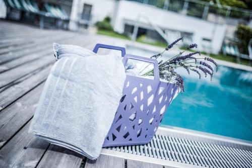 a purple basket with a potted plant next to a pool at Hotel Förstlerhof in Postal