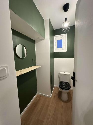 a bathroom with a toilet with a green wall at 145 désirs in Samer