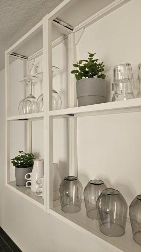 a white cabinet with glass vases and plants on it at Apartment Lu16 Three Bamberg - modern in zentral Lage in Bamberg
