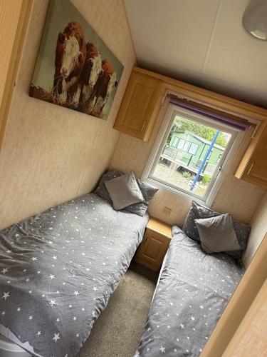 two beds in a small room with a window at Lake District Caravan Holiday in Millom