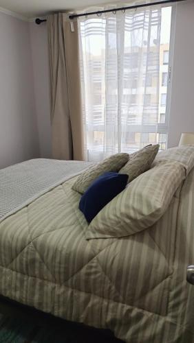 a bedroom with a bed with pillows and a window at angysol in Antofagasta