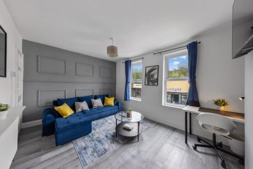 a living room with a blue couch and a desk at Cosy 2-Bed Home in the heart of Medway l Sleeps 5 in Gillingham