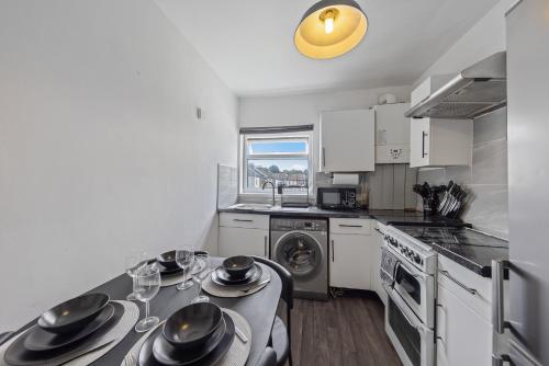 a kitchen with a table with dishes on it at Cosy 2-Bed Home in the heart of Medway l Sleeps 5 in Gillingham