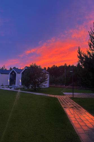 a sunset over a house with a brick driveway at NATURA APARTAMENTY Era in Ulinia