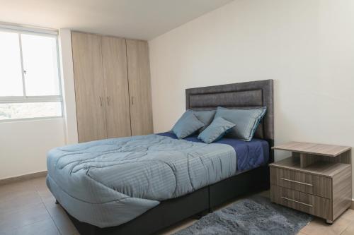 a bedroom with a bed with blue pillows and a table at Zona Rosa y Sector TURISTICO in Manizales