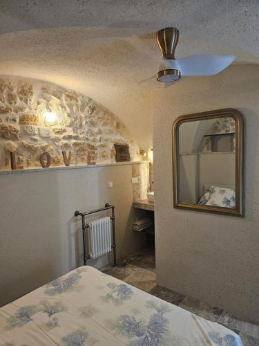 a bedroom with a ceiling fan and a mirror at Nid Minéral - Suite voûtée de charme au cœur de Vallon Pont d'Arc in Vallon-Pont-dʼArc