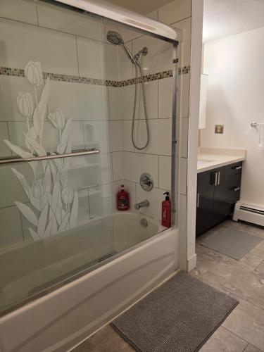a bathroom with a shower with a glass door at Maplewood Hostel in Vancouver