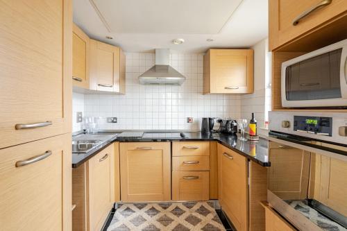 a kitchen with wooden cabinets and a microwave at Amazing River view 2 bedroom apartment, sleeps 6 , balcony and parking in London