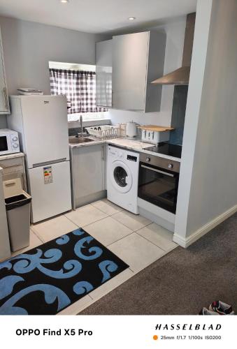 a kitchen with a stove and a washer and dryer at Stunning maisonette available in Watford