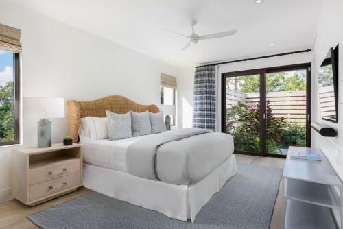 a white bedroom with a white bed and windows at A magnificent villa that is perfect to enjoy a quiet vacation in Leeward