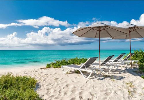 a group of chairs and an umbrella on a beach at A magnificent villa that is perfect to enjoy a quiet vacation in Leeward