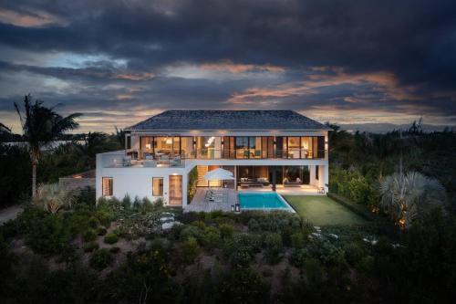 a large white house with a swimming pool at night at A magnificent villa that is perfect to enjoy a quiet vacation in Leeward