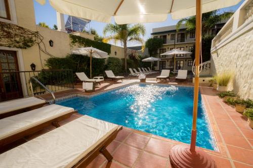 a swimming pool with chairs and an umbrella at Don Antonio Posada in Colonia del Sacramento
