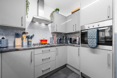 a white kitchen with white cabinets and appliances at Prestige Rooms MCR - Close to City Centre-Etihad Stadium - Fast WIFI in Manchester