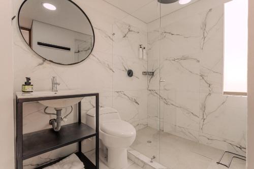 a white bathroom with a toilet and a mirror at Soy Local Parque La 93 in Bogotá