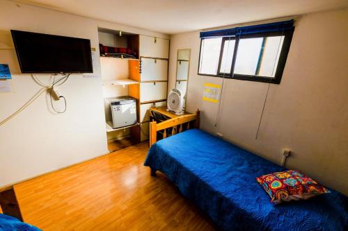 a small room with a bed and a television at Hostal Pampaloja Antof in Antofagasta
