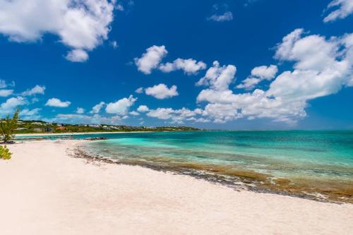 a beach with the ocean and a blue sky at Compact one bedroom villa right on the beach in Turtle Cove