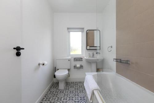 a white bathroom with a toilet and a sink at Pebble in Carbis Bay