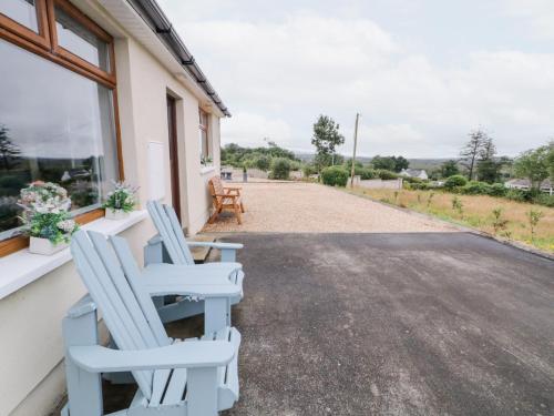 two blue chairs sitting on the porch of a house at Ard na Gréine in Kilrean