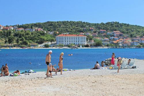 a group of people on a beach near the water at Apartments and rooms with parking space Trogir - 13102 in Trogir