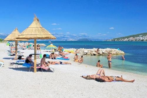 a group of people laying on a beach at Apartments and rooms with parking space Trogir - 13102 in Trogir