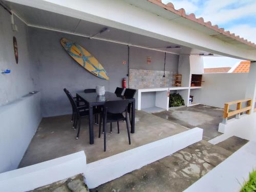 a table and chairs on a patio with a surfboard on the wall at Azure Vista Lodge in Nordestinho