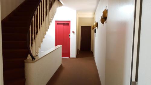 a hallway with a red door and stairs at Spalenbrunnen Hotel & Restaurant Basel City Center in Basel