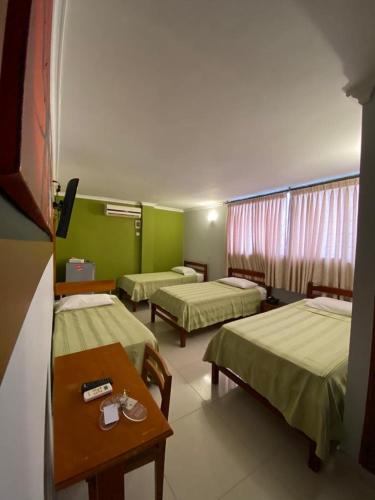 a hotel room with three beds and a table at Hotel San Francisco in Barranquilla