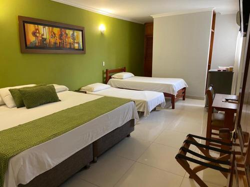 two beds in a room with green walls at Hotel San Francisco in Barranquilla