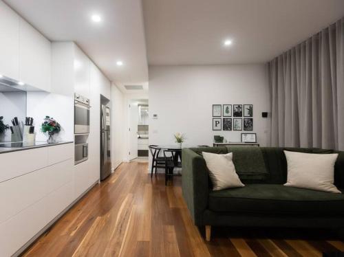 a living room with a green couch and a kitchen at The Chifley by Parbery Property Group in Campbell