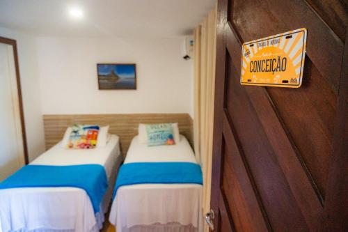 two beds in a room with a sign on the door at Hospedagem Junco Noronha in Fernando de Noronha
