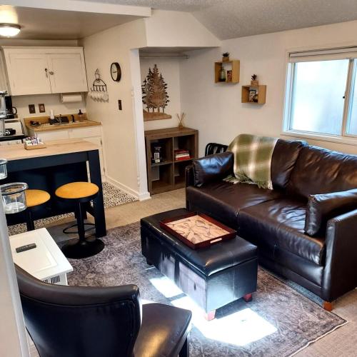 a living room with a leather couch and a table at The Nest Cottage with Hot Tub in Downtown Manitou Springs in Manitou Springs