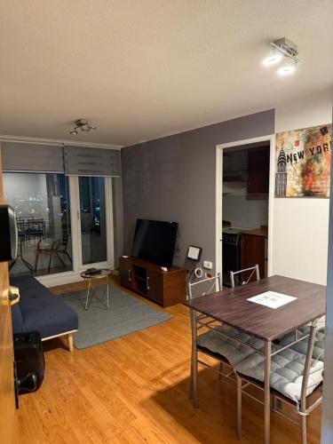 un salon avec une table et une télévision dans l'établissement Vista Mirador Centro con Balcón Dúo, à Concepción