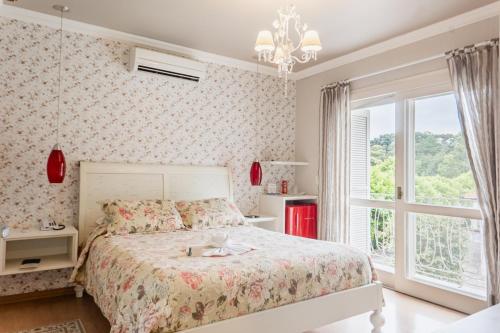 a bedroom with a large bed and a window at Doce Canela - Pousada de Charme in Canela