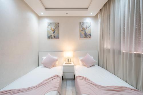 two beds in a small room with a lamp at LUXURY APARTMENT IN THE HEART OF MARRAKECH GUELIZ in Marrakech